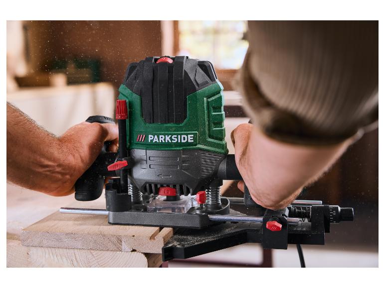 Een man gebruikt een bovenfrees om een stuk hout te bewerken, met zaagsel in de lucht.