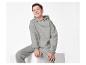 Garçon souriant en sweat à capuche et pantalon de survêtement gris, assis sur un cube blanc.
