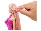 Barbiepop met lang, kleurrijk haar en een hand die een 'LOVE' haarclip vasthoudt.