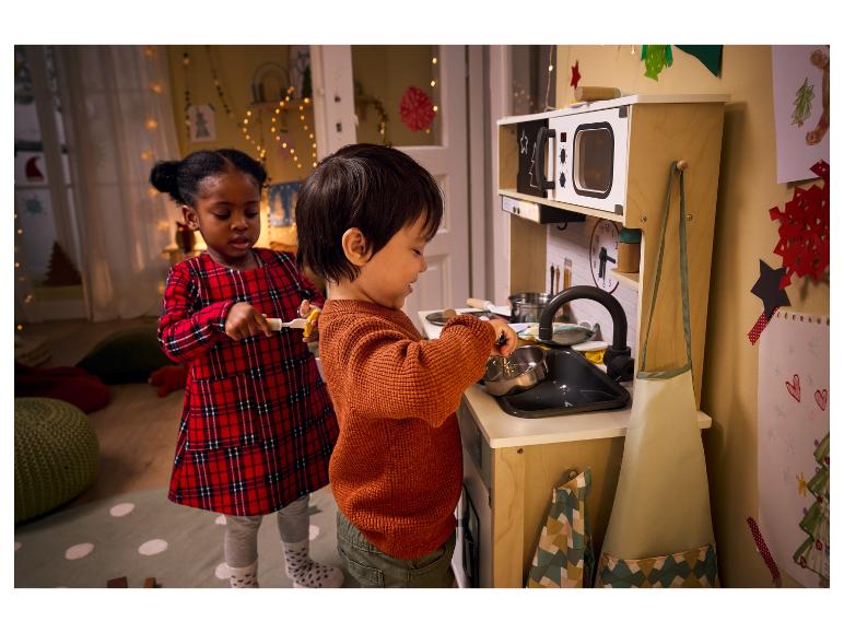 Twee kinderen spelen in een speelkeuken met een oven en een gootsteen.