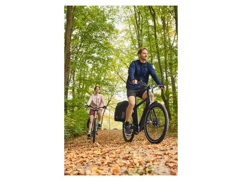 Twee mensen op fietsen op een bospad bedekt met herfstbladeren.