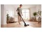 Une femme passe l'aspirateur sans fil SILVERCREST® sur le sol.