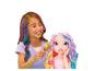 Fille souriante aux cheveux colorés brossant une poupée aux cheveux colorés