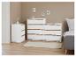 Drie witte ladekasten met houten accenten in een slaapkamer.