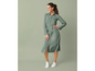 Een vrouw in een groene jurk met witte sneakers.