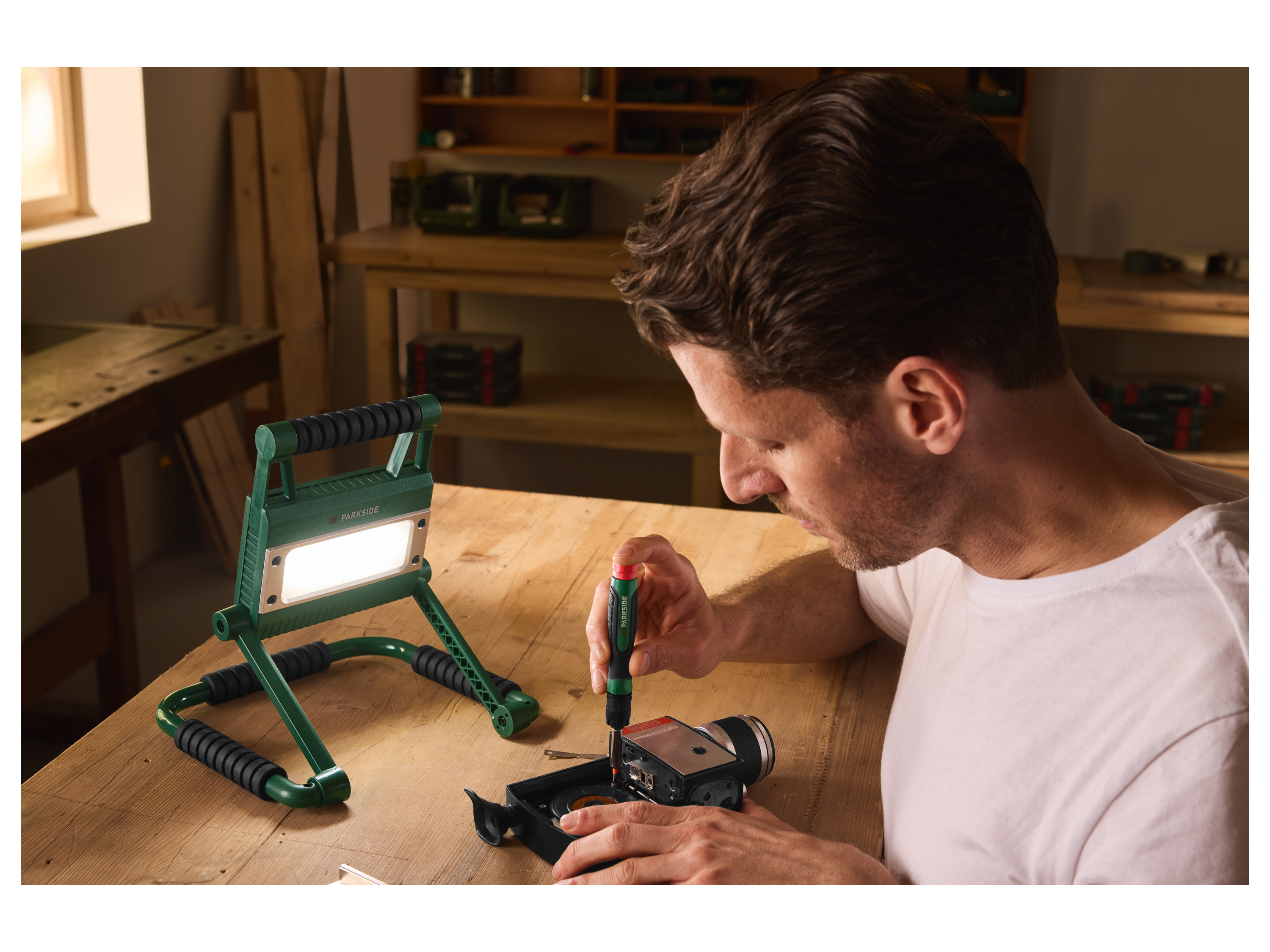 Homme travaillant dans un atelier éclairé par le projecteur LED PARKSIDE.