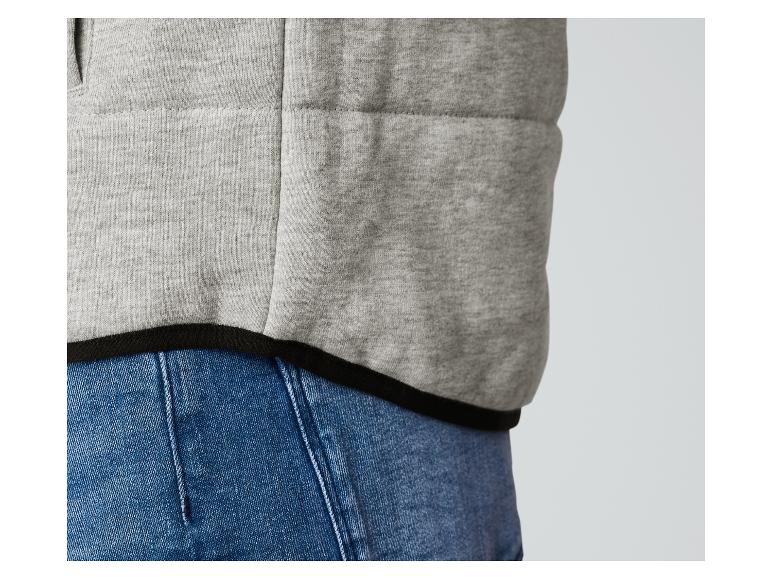 Un gilet gris avec une bordure noire sur un jean bleu.