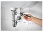 Des mains d'homme réparant des tuyaux sous un lavabo avec une pince.