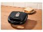 Zwart tosti-apparaat op houten aanrecht met sneetjes brood.