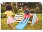 Deux enfants jouent sur une aire de jeux en bois avec toboggan dans le jardin.