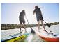 Deux personnes pagaient debout sur des planches de paddle gonflables Crivit.