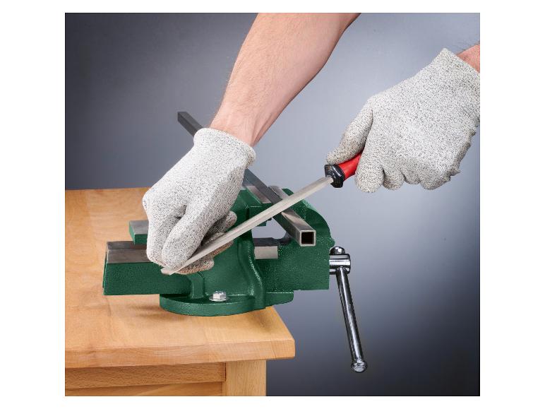 Een hand in een werkhandschoen gebruikt een vijl op een metalen staaf in een bankschroef.