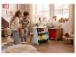 Deux enfants jouent avec un étal de marché en bois et des jouets dans une pièce décorée pour les fêtes.