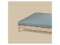 Licht houten bed met een blauwgroen hoeslaken.