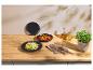 Assiettes de pâtes et de soupe dans des bols noirs, avec des couverts en cuivre et de l'huile sur une table en bois.