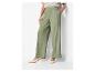 Vrouw in groene wide-leg broek, gestreept t-shirt en beige kitten heel schoenen.
