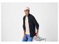 Homme souriant en casquette beige, cardigan bleu marine et jean.