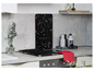 Une plaque de cuisson noire avec un dosseret de style terrazzo et un gant de four rouge.