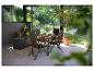 Buiten eethoek met houten tafel en opvouwbare rieten stoelen op een terras.