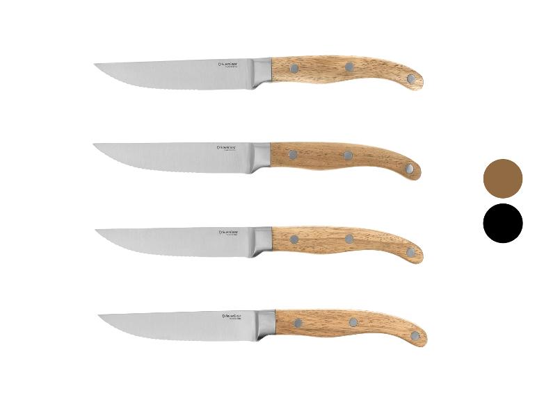 Quatre couteaux à steak avec manches en bois et lames dentelées.