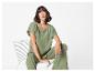 Vrouw in een groene getextureerde top en bijpassende wijde broek, zittend op een witte stoel.