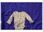 Babyromper met bloemenpatroon en kanten details op paarse wafelstof.