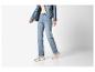 Persoon draagt een lichtblauwe spijkerjas, jeans en beige sneakers.