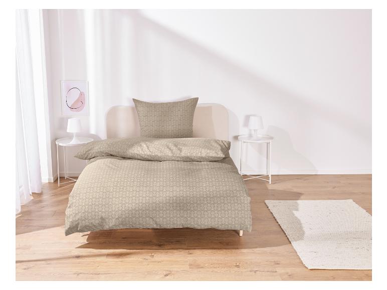 Beige beddengoed met geometrisch patroon op een bed.