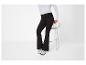 Vrouw in zwarte flared broek en witte longsleeve top, zittend op een kruk.