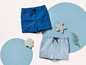 Deux shorts pour garçon sur le thème de la mer : un bleu avec des coquillages et un bleu clair.