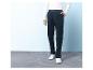 Man draagt donkerblauwe corduroy broek en witte sneakers.