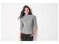 Een vrouw draagt een grijze turtleneck en zwarte broek.