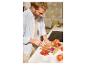 Homme coupant des tomates sur une planche à découper en bambou avec un tiroir.