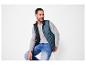 Man draagt een blauwe bodywarmer, een grijze longsleeve en jeans.
