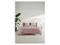 Housse de couette rose à pois blancs sur un lit avec tête de lit en bois, plante et table.