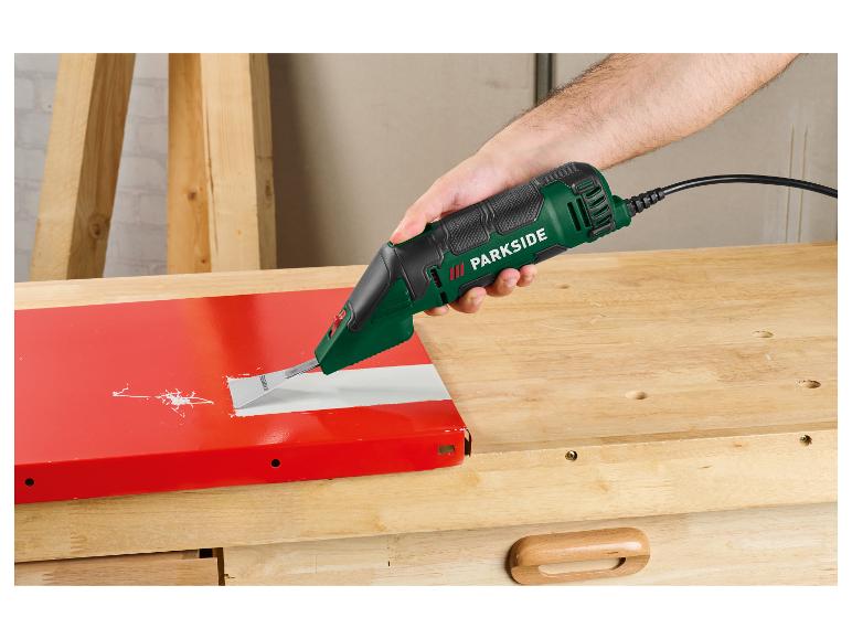 Man verwijdert verf van een rood oppervlak met een oscillerende schuurmachine op een houten tafel.
