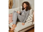 Een vrouw draagt een grijze pyjama met de tekst 'Natural Beauty Within' op de bank.