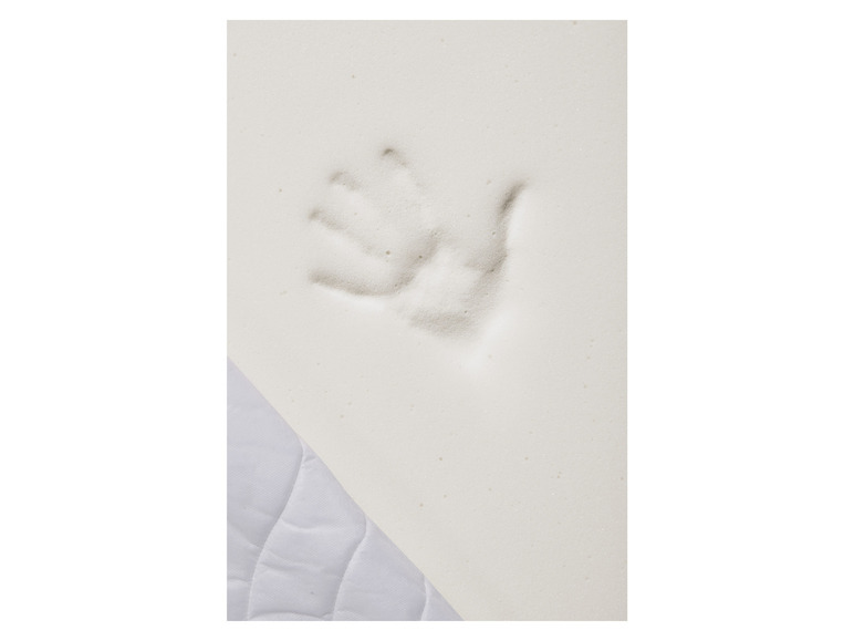 Une empreinte de main dans un matelas en mousse blanche.