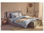 Slaapkamer met grijs bed, lichtblauw geruit beddengoed en decoratieve kussens.