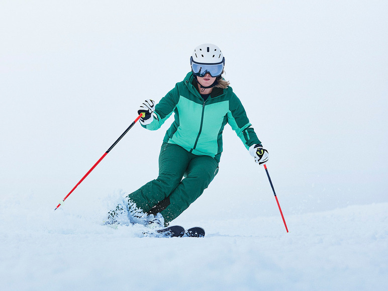 Een vrouw in skikleding skiet met ski's en stokken.
