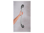 Een hand houdt een zilverkleurig metalen handvat vast dat aan de muur is bevestigd.