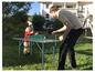 Een volwassene en een kind spelen tafeltennis in de tuin.