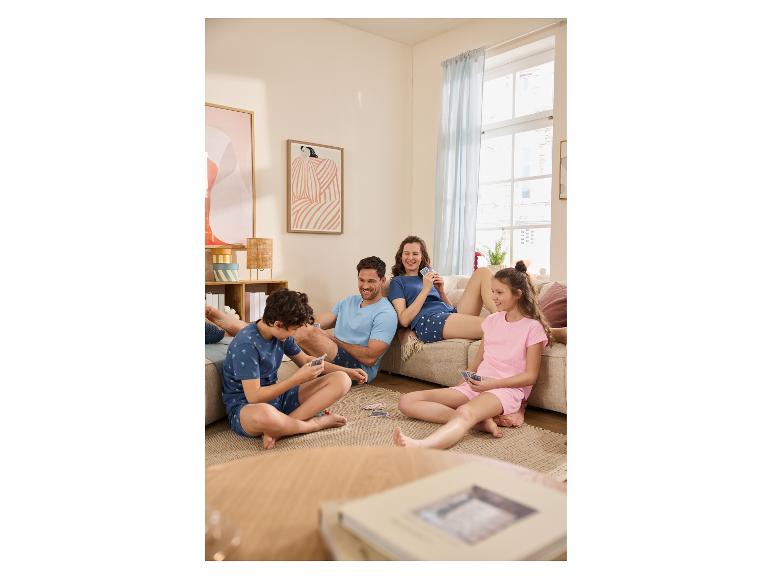 Familie in bijpassende pyjama's speelt kaarten in een gezellige woonkamer.