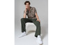 Man in een gebloemd overhemd, groene broek en witte Vans sneakers