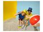 Couple en tenue d'été et chapeaux bob, avec un ballon de plage, sur fond jaune et bleu.