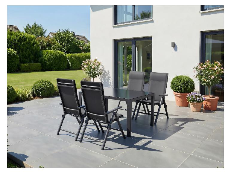 Tuinmeubelset met zwarte tafel en stoelen op een terras, omringd door groen.