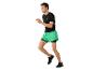 Man in zwart shirt en groene shorts aan het rennen.