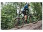 Un homme fait du vélo sur un VTT électrique gris avec des pneus Maxxis dans une forêt.