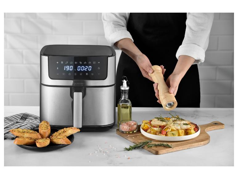 MasterPRO airfryer met gekookt eten en een persoon die kruiden toevoegt.