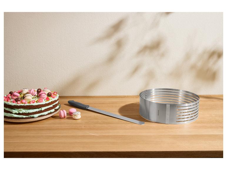 Gâteau avec macarons, couteau à gâteau et moule à découper réglable sur une table en bois.